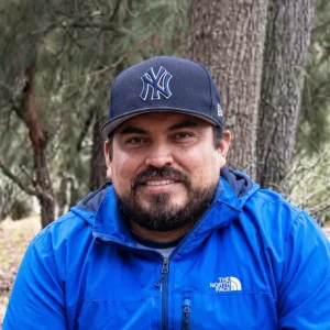 Retrato de Hombre con barba, chaqueta azul y gorra en un parque