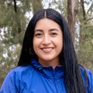 Retrato de Mujer con cabello negro con chompa azul en un parque